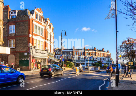 Fußgänger, die an einem sonnigen Winternachmittag auf der Fortis Green Road, Muswell Hill, den Zebrastreifen überqueren, London, Großbritannien Stockfoto