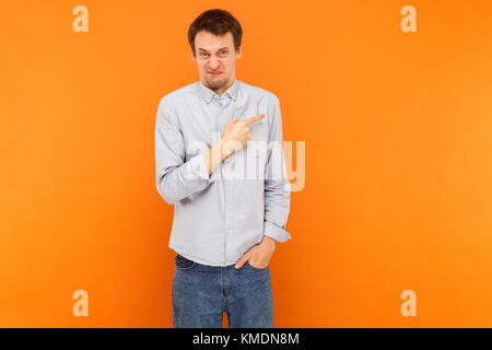 Zorn mann Zeigefinger bei copy Space und Kamera. Studio shot, orange Hintergrund Stockfoto