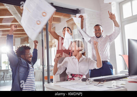 Ausgelassene Geschäftsleute feiern, werfen Papierkram Overhead im Büro Stockfoto