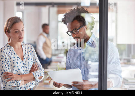 Unternehmer und Unternehmerin diskutieren Papierkram im Büro Stockfoto