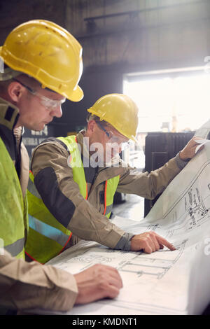 Ingenieur und Stahlarbeiter diskutieren Baupläne in Stahlwerk Stockfoto