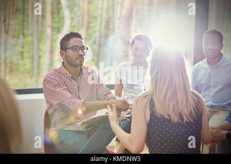 Aufmerksamer Mann, der der Frau in der Gruppentherapie zuhört Stockfoto