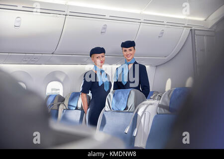 Portrait lächelnd, selbstbewusste Flugbegleiterinnen im Flugzeug Stockfoto