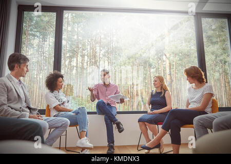 Männlicher Therapeut mit Clipboard führt Gruppentherapie-Sitzung Stockfoto