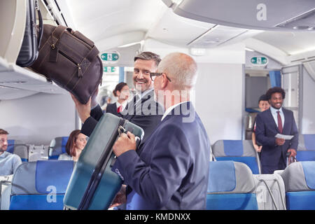 Geschäftsleute, die Gepäck im Flugzeug in das Ablagefach einladen Stockfoto