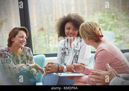 Lächelnde Frauen sprechen in der Gruppentherapie Sitzung Stockfoto