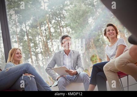 Lächelnde Menschen sprechen in der Gruppentherapiesitzung Stockfoto