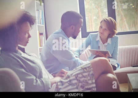 Weibliche Therapeutin mit digitalen Tablette beruhigende Mann in Paare Therapie Sitzung Stockfoto