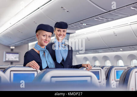 Portrait lächelnd, selbstbewusste Flugbegleiterinnen im Flugzeug Stockfoto