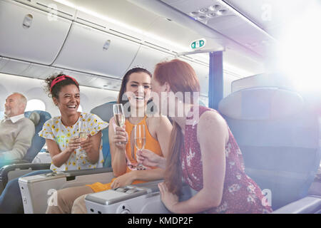 Junge Freundinnen trinken Champagner in der ersten Klasse im Flugzeug Stockfoto