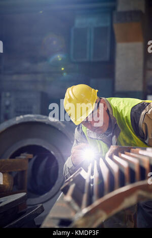 Fokussierter Stahlarbeiter mit Taschenlampe Untersuchung Stahlteil in Stahlwerk Stockfoto