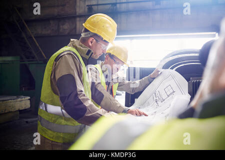 Ingenieur und Stahlarbeiter untersuchen Baupläne in Stahlwerk Stockfoto
