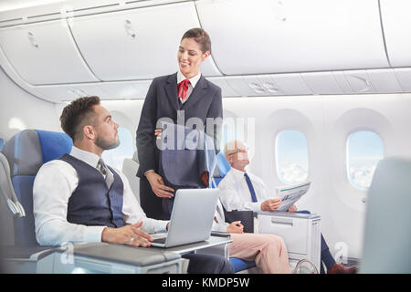 Flight Attendant im Gespräch mit Unternehmer Arbeiten am Laptop auf dem Flugzeug Stockfoto