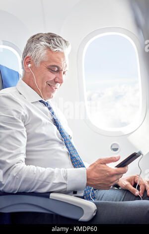 Geschäftsmann hört Musik mit Kopfhörern und MP3-Player an Flugzeug