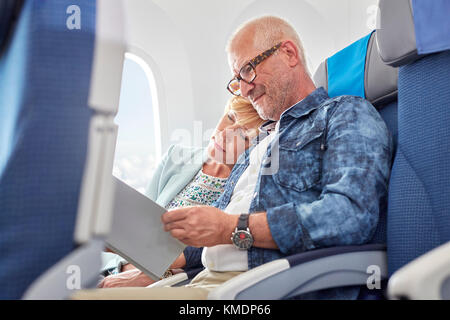 Liebevoll reifen Paar schlafen und lesen auf Flugzeug Stockfoto