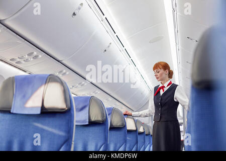 Weibliche Flugbegleiterin im leeren Flugzeug Stockfoto
