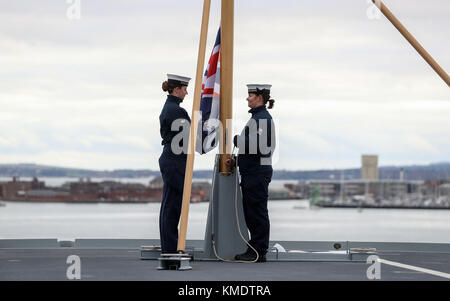 Auf 0001 Donnerstag, 7. Dezember Royal Navy ratings Vollmatrosen, Ellie Smith (links) und Vollmatrosen, Jessica Hewes Praxis heben die Fahne auf dem Flugdeck der HMS Queen Elizabeth vor ihrer Inbetriebnahme Zeremonie am Donnerstag in Portsmouth Embargo Stockfoto