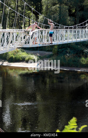 Ein Junge, der gerade von der Cambus O’May Fußgängerbrücke über den Fluss Dee abspringt, der in Storm Frank schwer beschädigt wurde Stockfoto