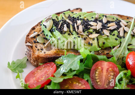 Avocado auf Toast mit seitlichem Salat Stockfoto