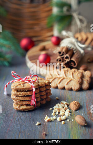 Auf Sloseup almond Cookies mit Zimtstangen, Klee, Mandeln und Weihnachtsbaum Zweige auf rustikalen hölzernen Hintergrund Stockfoto