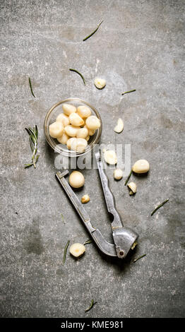 Knoblauch in einer Glasschale und drücken Sie Knoblauch. Auf einem Stein. Stockfoto