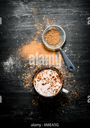 Tasse heiße Schokolade mit zerquetschten Kakao. Auf schwarzem Hintergrund im Landhausstil. Stockfoto