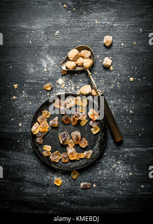 Brauner Rohrzucker. auf einem schwarzen Hintergrund im Landhausstil. Stockfoto