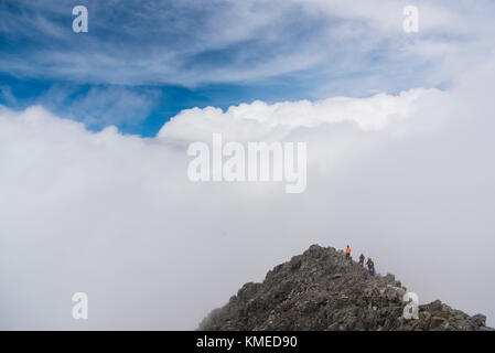 Eine Gruppe von Bergsteigern auf einen kleinen Gipfel von Wolken am Nevado de Toluca Vulkan in Estado de Mexico, Mexiko umgeben. Stockfoto