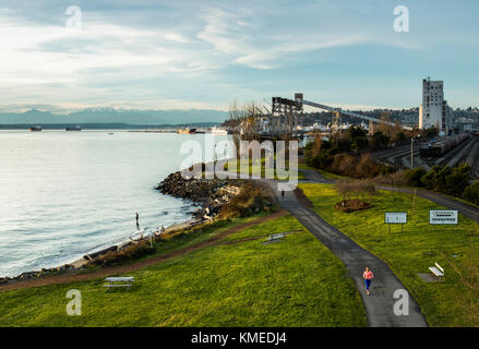 Ein Läufer Joggen entlang der Kante des Puget Sound in Seattle, WA an einem bewölkten Abend. Stockfoto