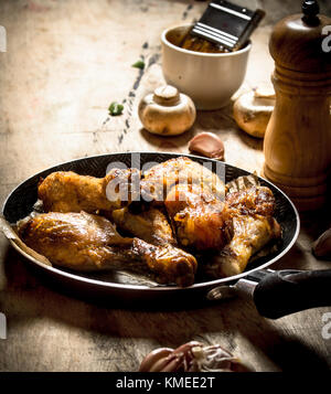 Fried Chicken Beine in einer Pfanne mit Tomaten, Pilze und Knoblauch. Stockfoto