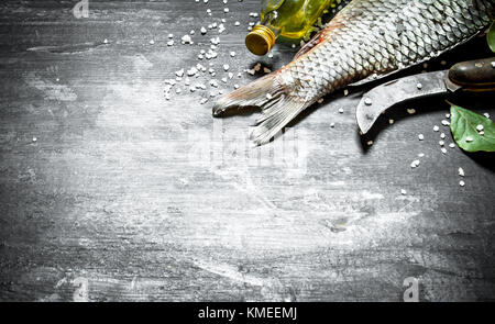 Fisch mit einem alten Schinkenmesser und Olivenöl. auf einem schwarzen Holz- Hintergrund. Stockfoto