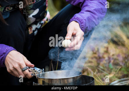 In der Nähe der Hände der weiblichen Camper holding Wachtelei über Dampfenden backpacking Topf, Jackson, Wyoming, USA Stockfoto