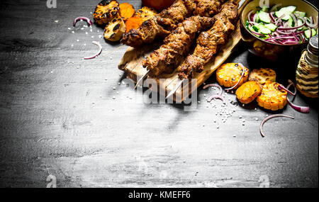 Shish Kebab am Spieß mit gegrilltem Gemüse und frischer Salat. Auf dem schwarzen Holztisch. Stockfoto