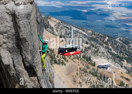 Weibliche Kletterer klettern Fels mit Bergen und Jackson Hole Gondel im Hintergrund, Jackson Hole, Wyoming, USA Stockfoto