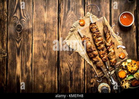 Gegrilltes Gemüse mit einem duftenden Shish Kebab aus Hammelfleisch. auf Holz- Hintergrund. Stockfoto