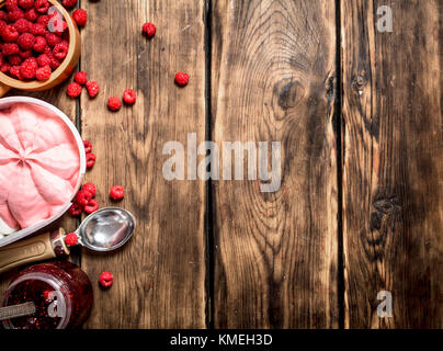 Himbeermarmelade mit Eis und Waldbeeren. Auf einem Holztisch. Stockfoto