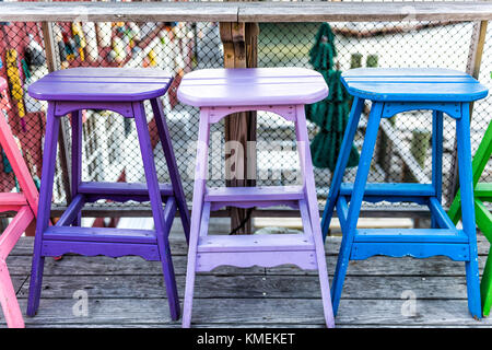 Bunte lebendige Stühle gemalt Lila, Blau und Grün auf die Waterfront Bar Restaurant Stockfoto