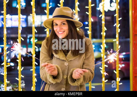 Mädchen, dass Feuer funkelt mit festlich beleuchteten Hintergrund Stockfoto