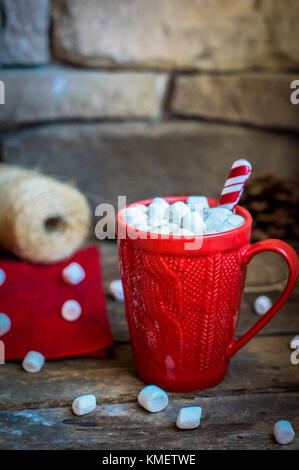 Rot gestrickt Becher mit heißer Schokolade und Marshmallows auf hölzernen Hintergrund Stockfoto