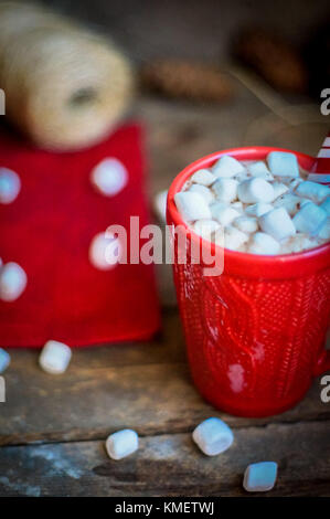 Rot gestrickt Becher mit heißer Schokolade und Marshmallows auf hölzernen Hintergrund Stockfoto