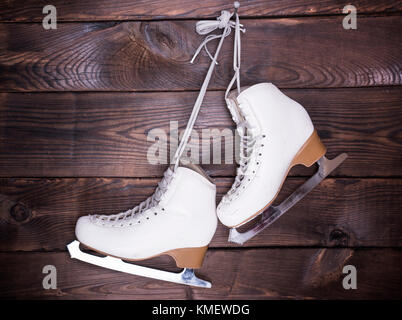 Weiß verwendet Leder Damen Schlittschuhe hängen an einem Nagel auf braunem Holz- Hintergrund Stockfoto