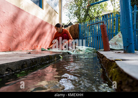 Eine arme Frau, die sich in indien an einem Wasserlauf von Hand kleidet Stockfoto