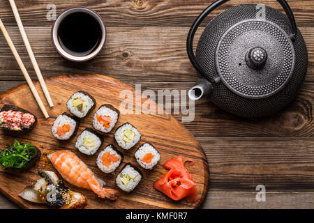 Sushi, Tee- und Sojasauce auf hölzernen Hintergrund Stockfoto