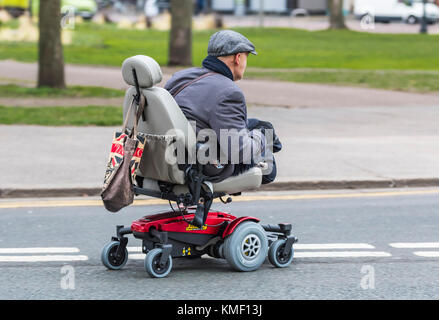 Doppeltes amputee Mann ohne Beine reiten in einem Mobility Scooter auf einer Straße in Großbritannien. Stockfoto