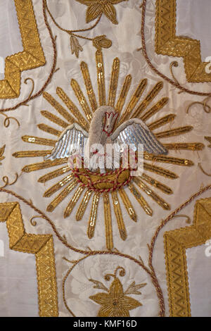 Ein dekoratives römisch-goldenes, römisch-katholisches Seidengewand, in dem die christliche Symbolmutter Pelican ihre drei jungen Küken füttert. Stockfoto