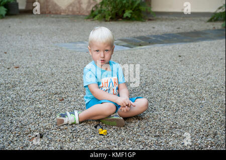 Drei Jahre alte Junge spielt mit Kies Stockfoto