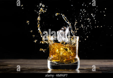 Glas Whisky in einem dunklen Ambient mit Ice Cube fallen ein Spritzen Stockfoto