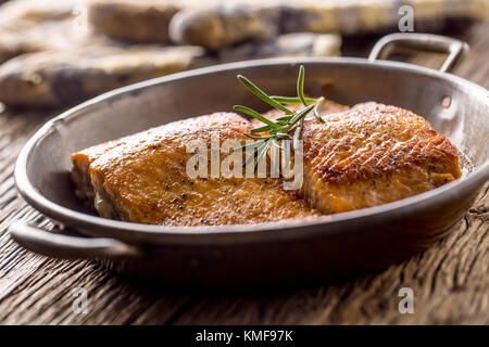 Lachs. Zwei saftigen Lachs Steaks in der Pfanne braten mit Kraut Dekoration auf Eiche rustikal Tisch. Stockfoto