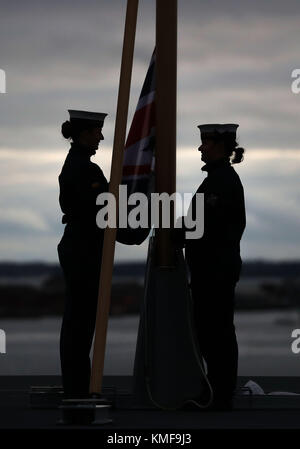 Royal Navy ratings Vollmatrosen, Ellie Smith (links) und Vollmatrosen, Jessica Hewes Praxis heben die Fahne auf dem Flugdeck der HMS Queen Elizabeth vor ihrer Inbetriebnahme Zeremonie am Donnerstag in Portsmouth Stockfoto