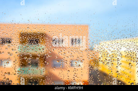 Regen fällt auf das Glas in den Hintergrund verschwommen flache Gebäude Stockfoto